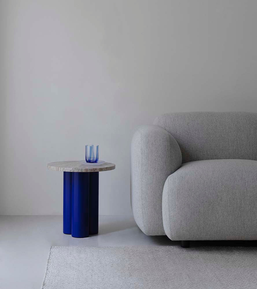 Ronde bijzettafel met licht travertijn blad en blauw stalen onderstel.