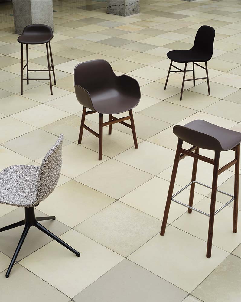 Grijze plastic barkruk met walnoothouten poten en metalen voetensteun, modern design. Normann Copenhagen.