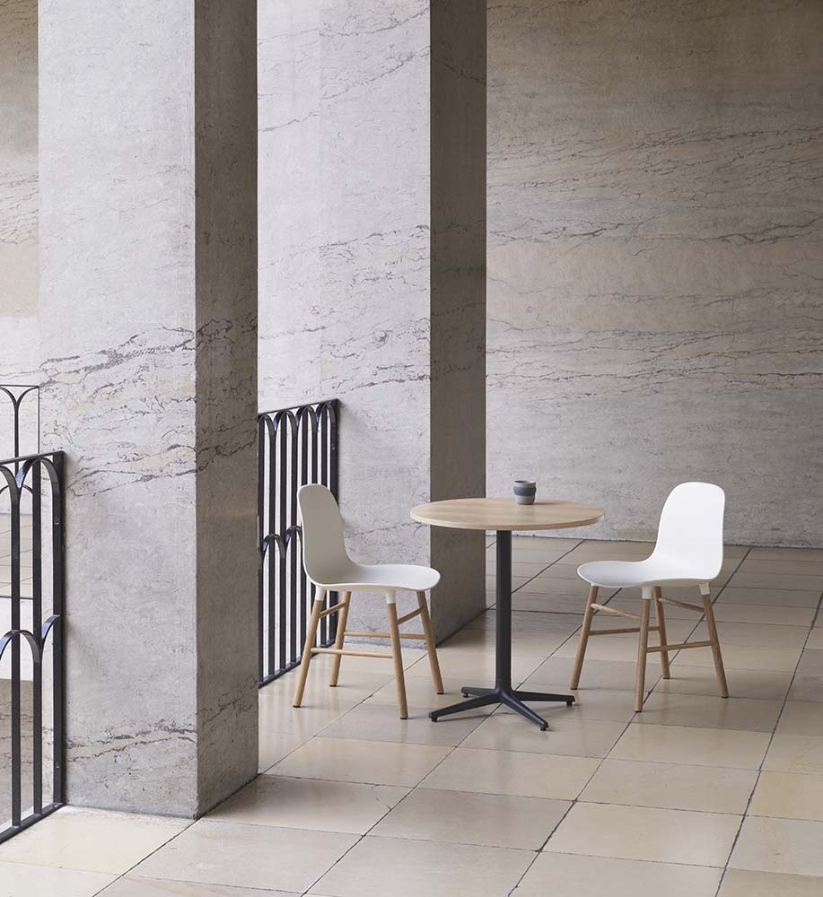 Grijze plastic stoel met eikenhouten poten, modern design, ideaal voor eetkamer of kantoor. Normann Copenhagen.