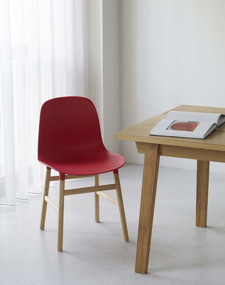 Blauwe plastic stoel met eikenhouten poten, modern design, ideaal voor eetkamer of kantoor. Normann Copenhagen.