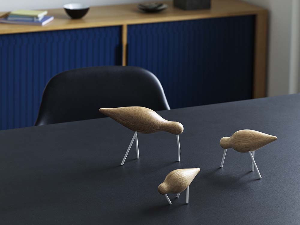 Moderne eikenhouten vogelvormige stoel met zwarte stalen poten.